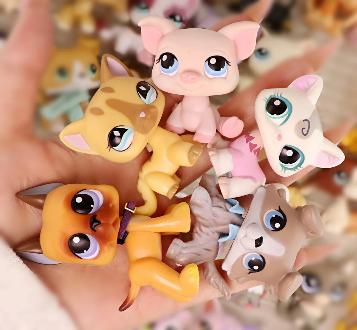 A hand holds a set of miniature pet animal figures in various colors and poses.