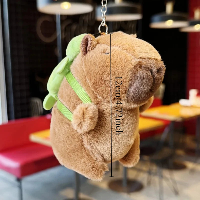 A brown capybara plush toy, representing a mother with four babies, is hanging by a gold chain.