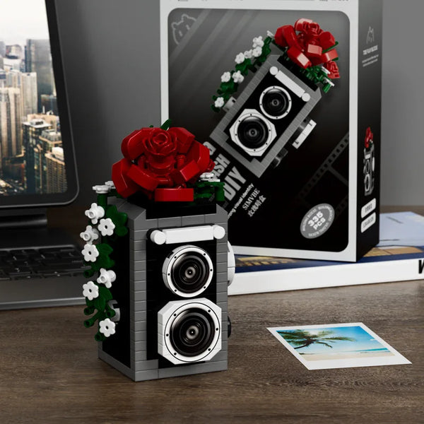 A building block set depicting a retro SLR camera with floral accents, displayed on a wooden surface.