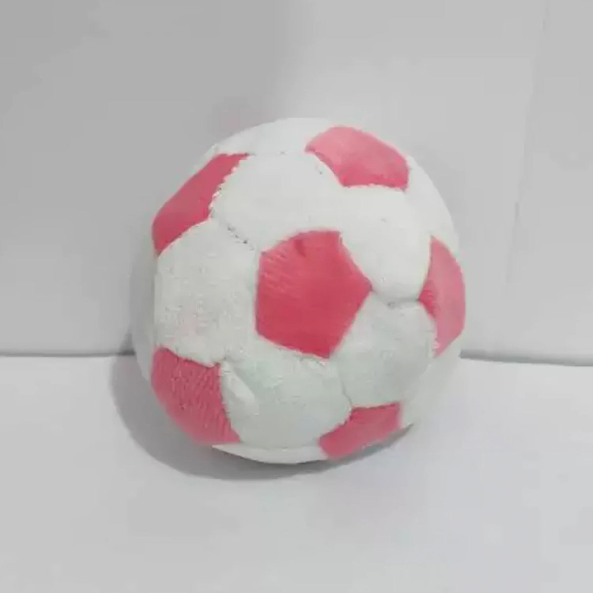 A single pink and white handmade crochet hacky sack ball.