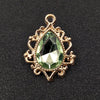 Gold plated water droplet charm featuring a faceted green crystal gemstone set in an ornate flower design