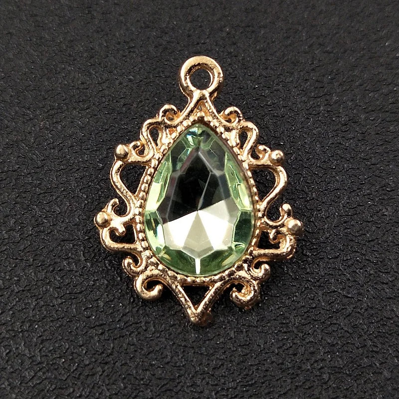 Gold plated water droplet charm featuring a faceted green crystal gemstone set in an ornate flower design