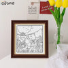 A framed black and white line art drawing of a bear hugging a rabbit surrounded by flowers for a coloring book.