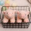 A pair of pink plush pig stuffed animals resting in a black wire basket.