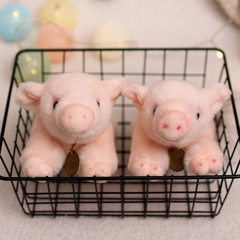 A pair of pink plush pig stuffed animals resting in a black wire basket.