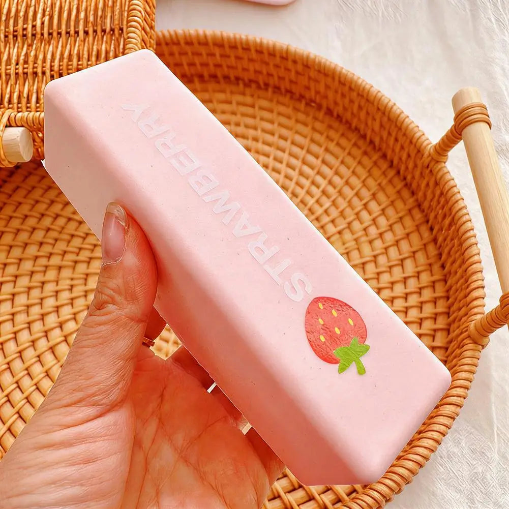 A pink strawberry milk squishy stress relief toy is held in a hand and placed inside a woven basket.