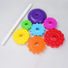A set of colorful plastic stacking rings in purple, green, blue, pink, and orange, along with a white stick.