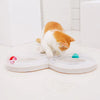 An orange and white cat is interacting with an interactive cat turntable toy featuring a tunnel and teaser wand.