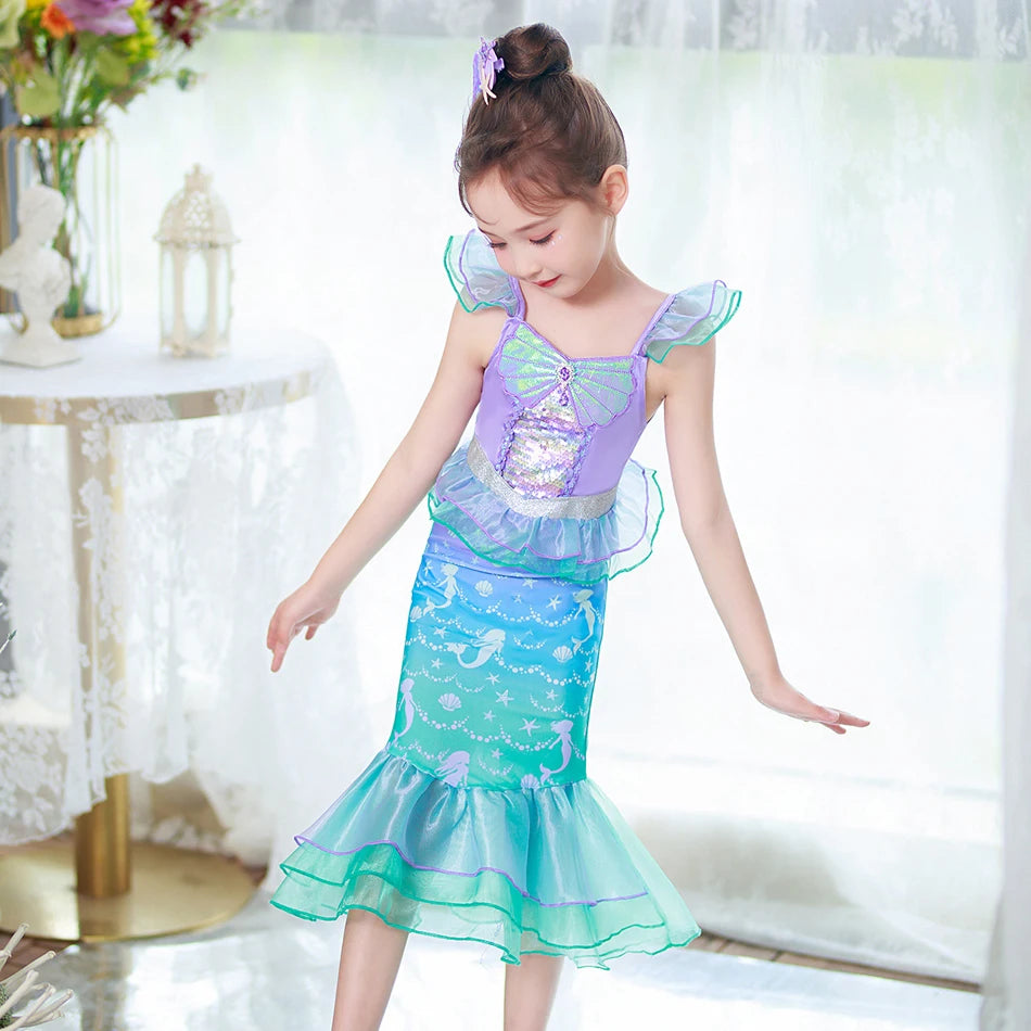 A young girl models a purple and teal mermaid fantasy dress with ruffled fishtail skirt.