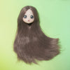 A close-up of a brown-haired Ball-Jointed Doll with large eyes against a light green background.