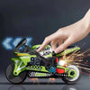A hand is holding a green and black motorcycle keychain fidget toy with spinning wheels and sparks.