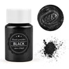 A small black glass jar with a white cap containing black pearl powder and a loose pile of the same powder.