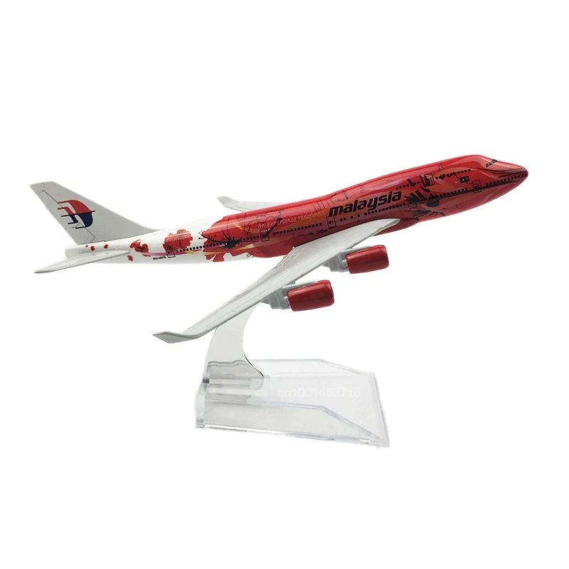 A diecast model of a Malaysia Airlines Boeing airplane in red and white paint on a clear stand.