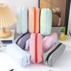 A collection of pastel and striped canvas pencil cases in various colors are displayed on a white surface.