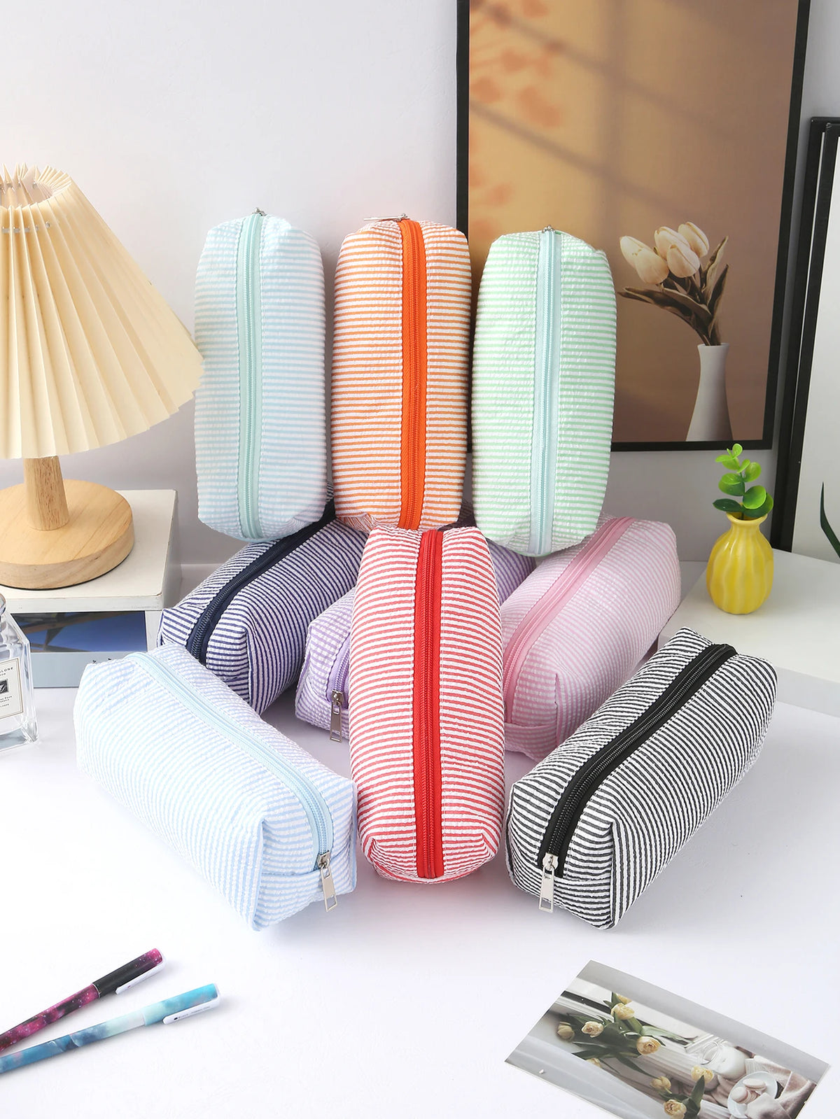 A collection of pastel and striped canvas pencil cases in various colors are displayed on a white surface.