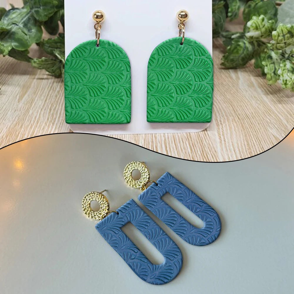 Two green oval earrings with a floral texture design displayed on a white background.