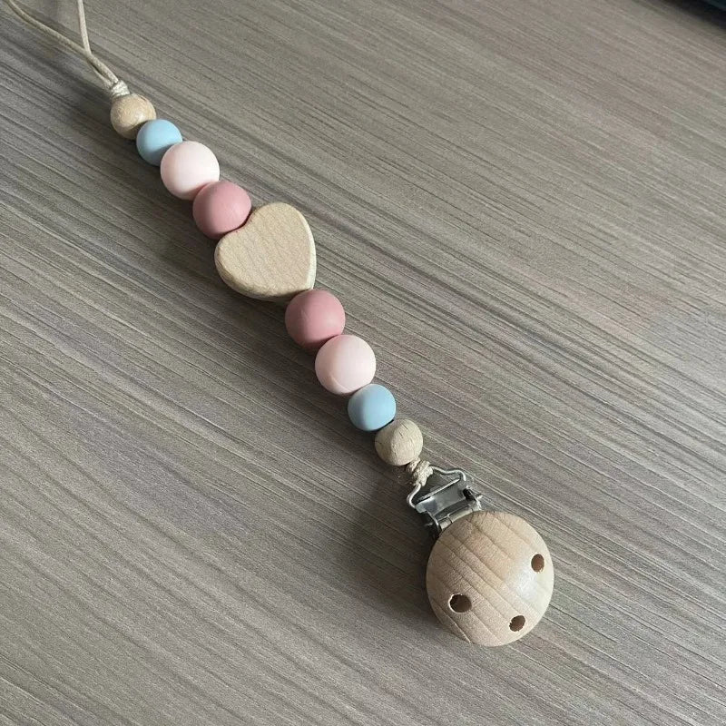A string of wooden and silicone beads forms a clip for a baby pacifier.