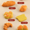 A collection of various baked goods including a pineapple bun, donut, whelk bun, baguette, windmill bau, slice of toast, croi
