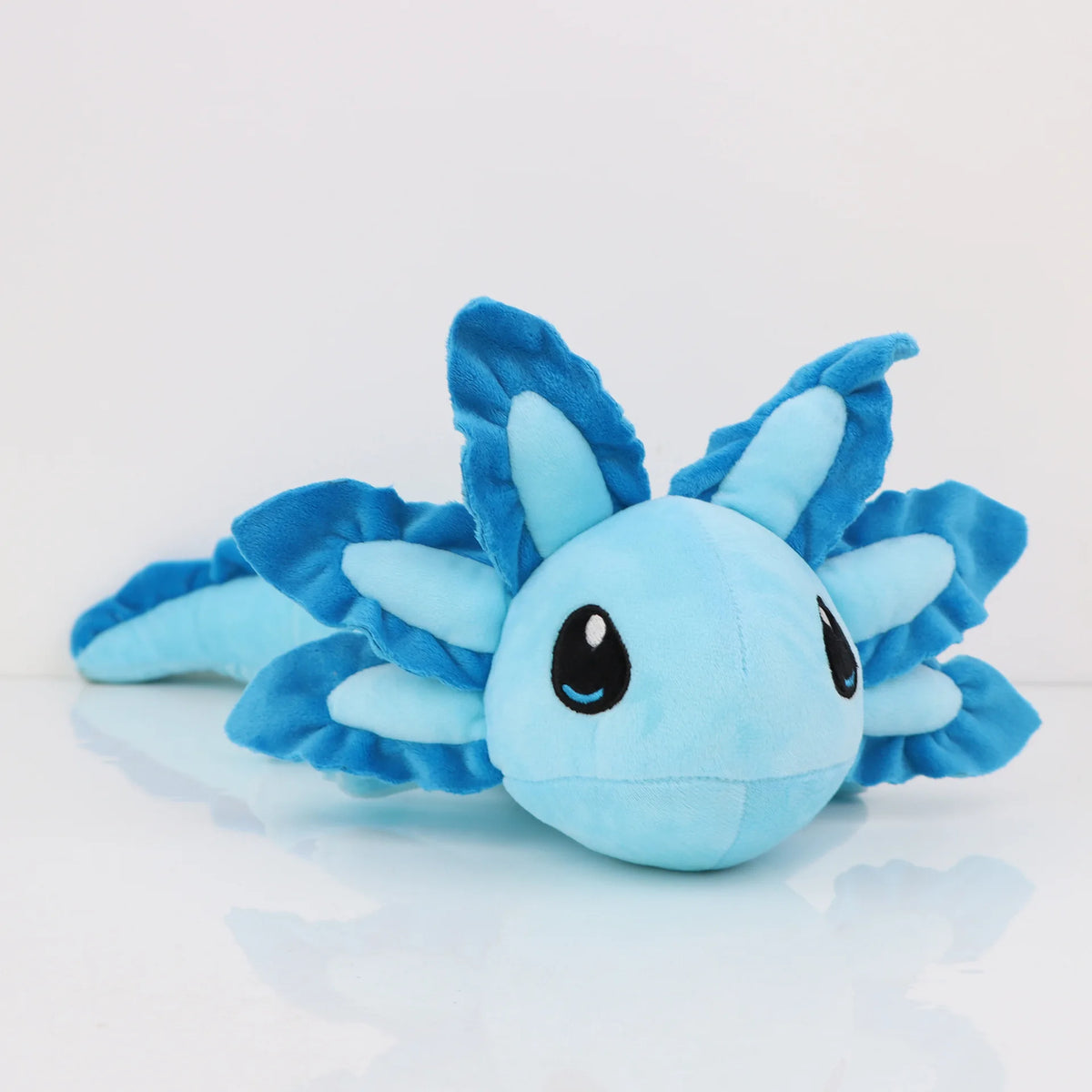 A soft blue and teal plush toy of an axolotl with spiky fins and large eyes.