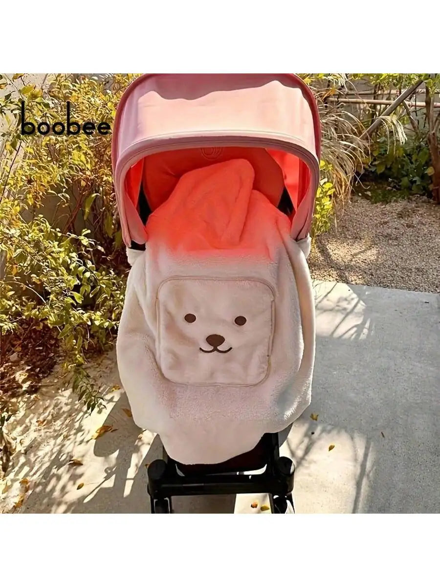 A pink baby windproof cape blanket with a white dinosaur design is displayed outdoors.