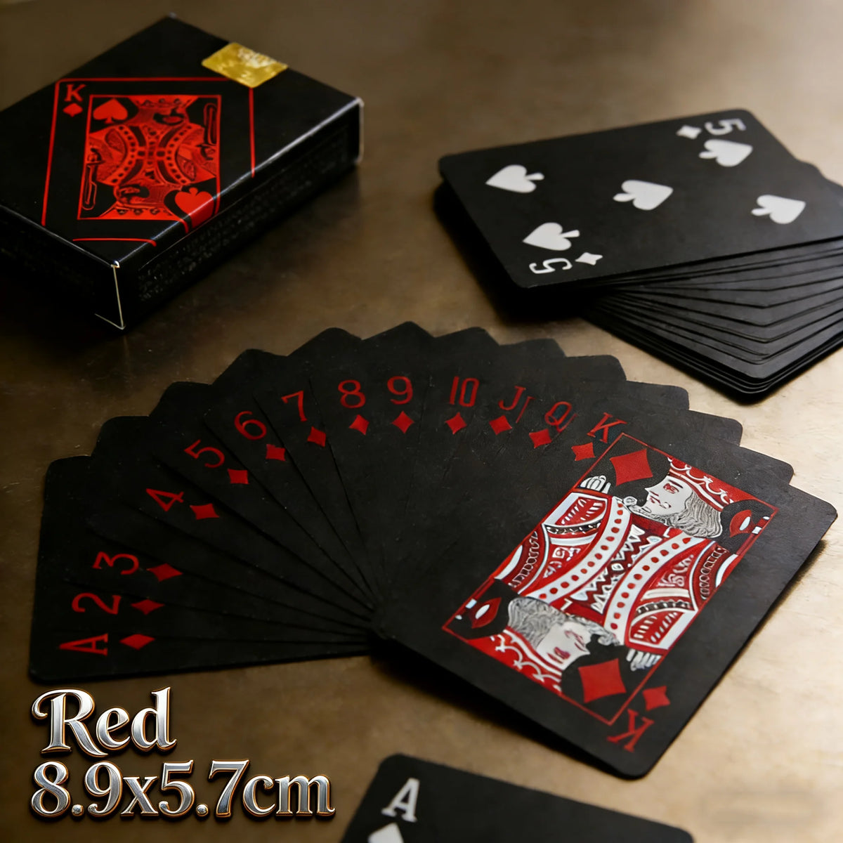 A spread of black playing cards with red aces and kings, alongside a box and a stack of cards.