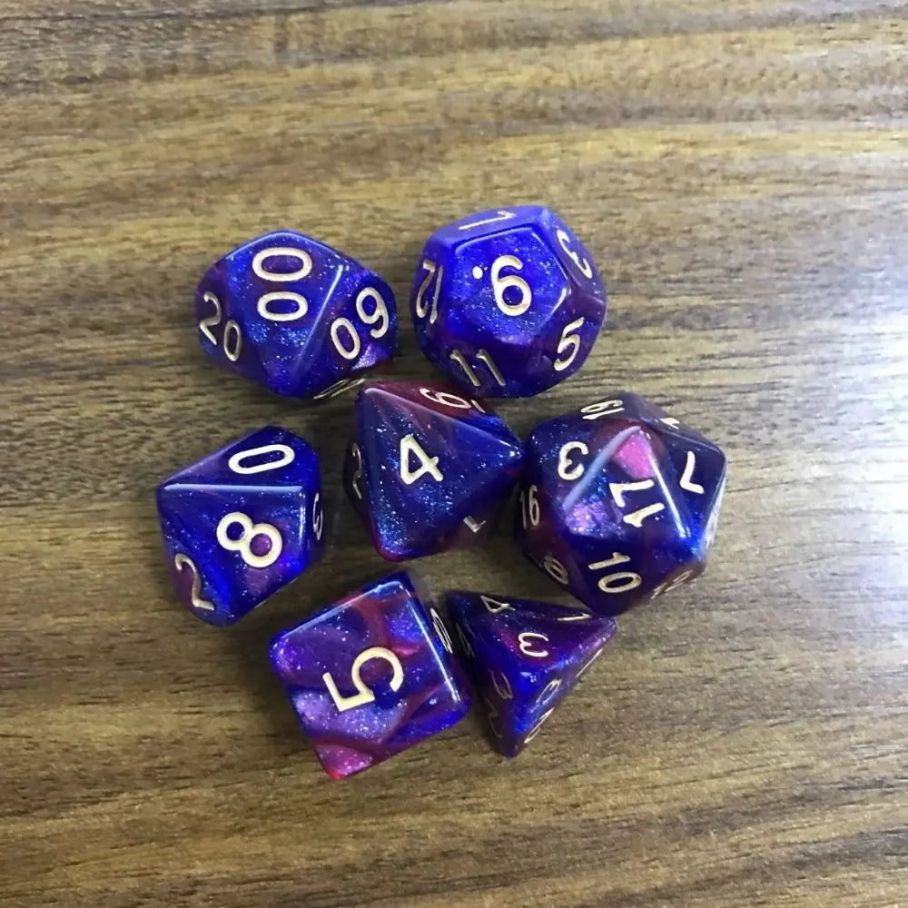 A set of seven polyhedral acrylic dice showing various numbers and colors on a wooden surface.
