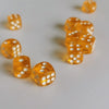 A close-up shot of several small, transparent orange dice scattered on a white surface.