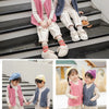 Two children wearing cozy lamb wool baby vests and light-colored pants sitting on stairs.