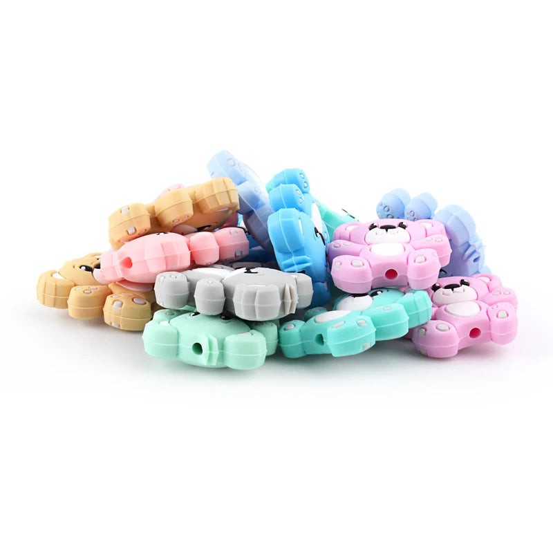 A collection of colorful silicone bear beads in various shades of pink, blue, and yellow for jewelry making.
