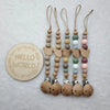 A string of wooden beads and clips in pastel colors, used as a baby pacifier clip.