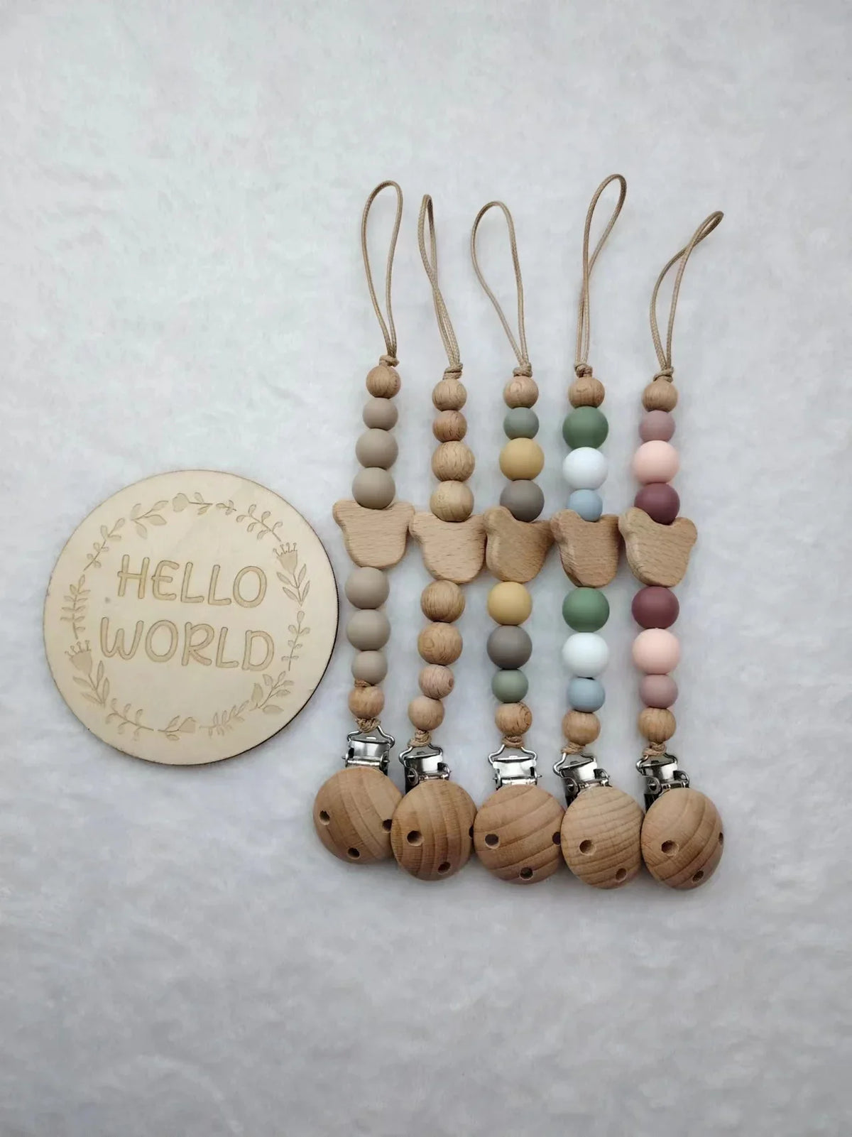 A string of wooden beads and clips in pastel colors, used as a baby pacifier clip.