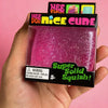 A hand holds a NeeDoh Nice Cube sensory fidget toy which is a glitter ice cube in a black box.