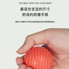 A hand holds an orange Montessori shape sorting cube with elastic bands.