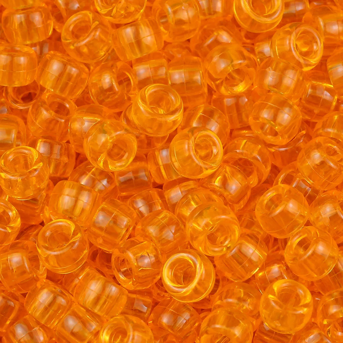 A pile of small, translucent orange pony beads for jewelry making and crafts.