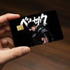A hand holds a black card featuring an anime character design with Japanese text and a gold fist symbol.