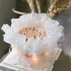A bouquet of pink roses wrapped in translucent tissue paper sheets for gift wrapping.