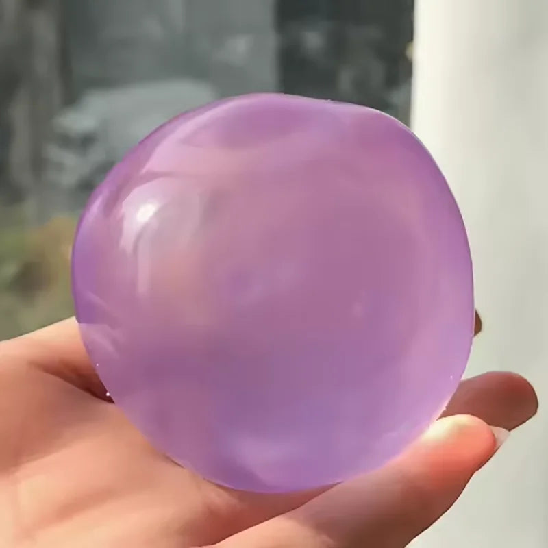 A hand holds a smooth, translucent lavender squeezy ball for stress relief.