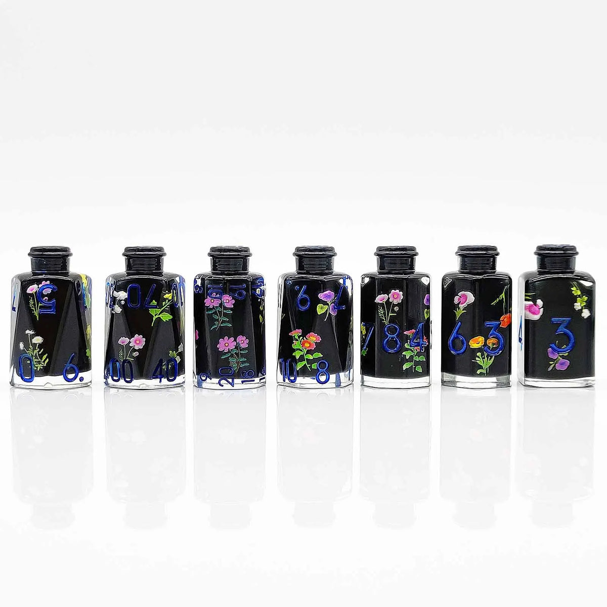 A set of seven floral resin potion bottles with numbered dice inside, displayed in a row.