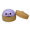 A purple bubble-spitting dumpling squishy stress relief toy in its beige container.