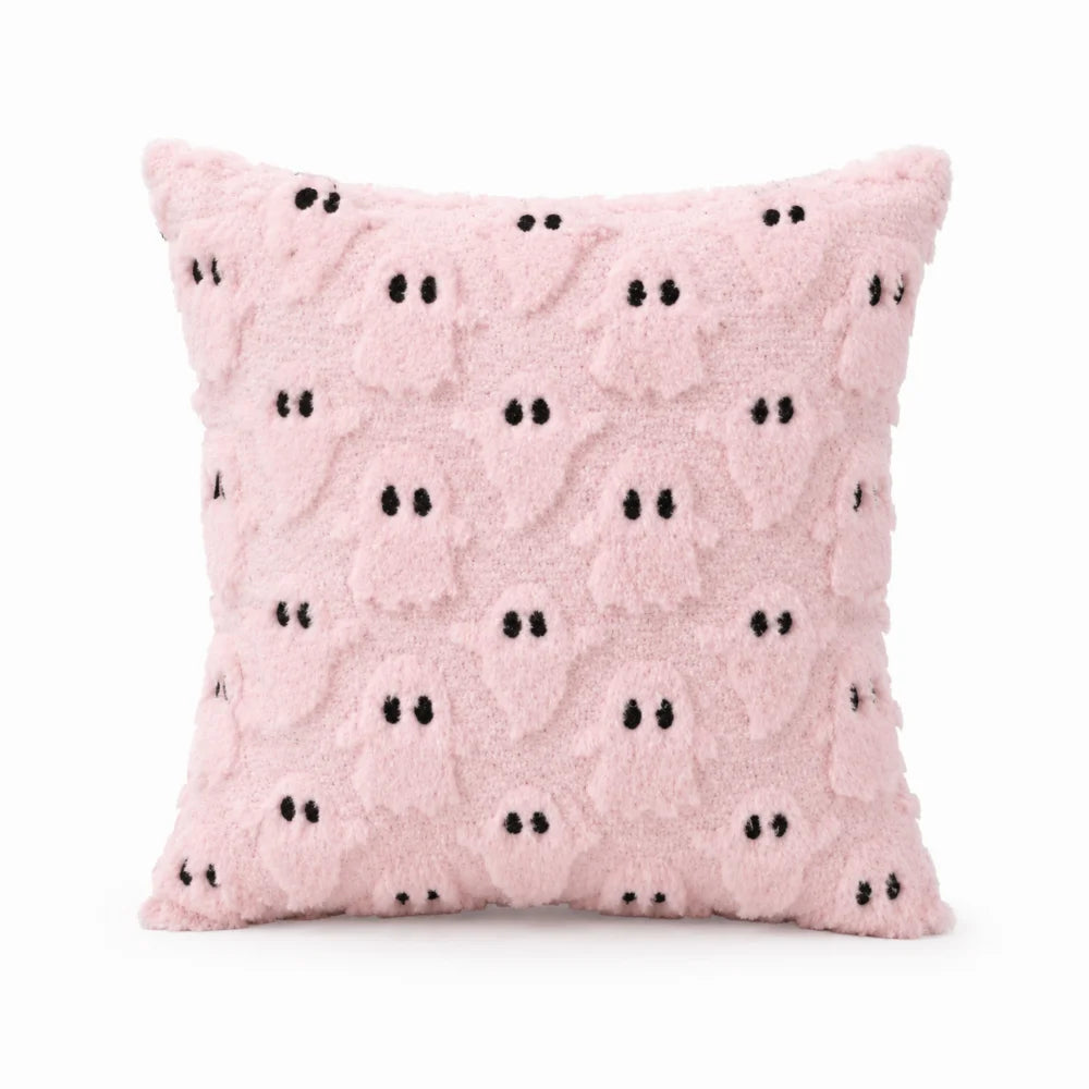 A pink fuzzy pillow with black ghost patterns.