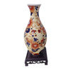 Blue and white porcelain flower vase with floral patterns on a dark stand.
