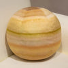 A spherical plush toy depicting an orange and yellow striped planet, resembling a solar system model.