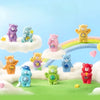 A collection of colorful Care Bears figurines in various sizes and colors standing on a green landscape with white clouds.