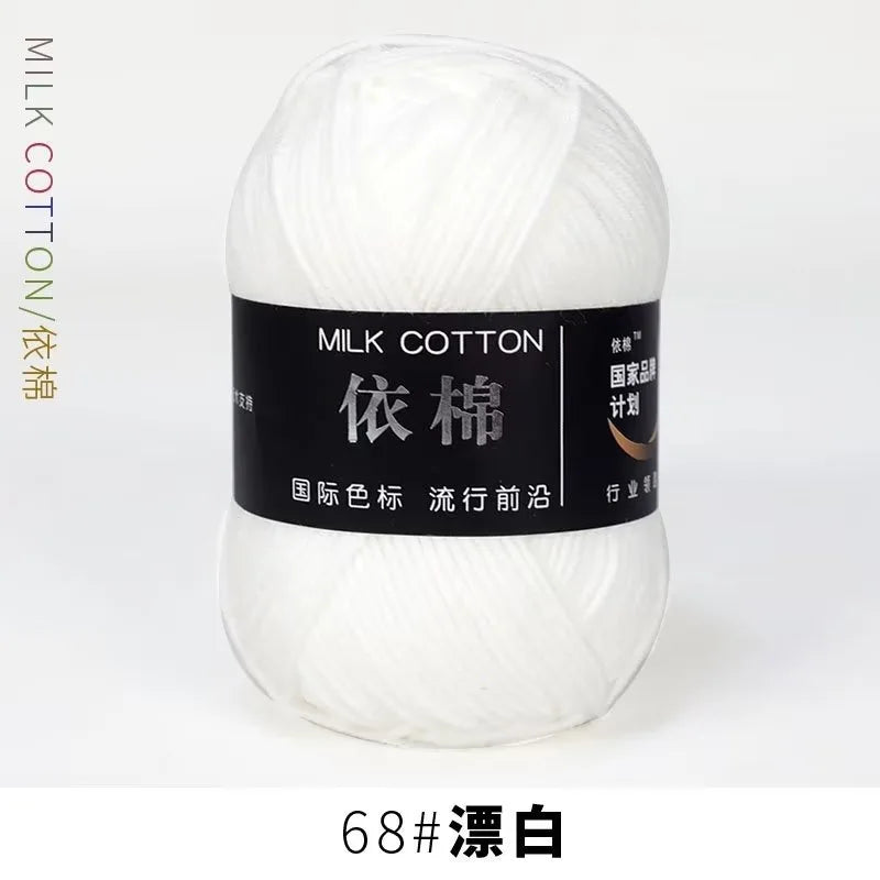 A ball of white milk cotton yarn labeled for international color standards and washing instructions.