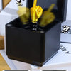 A black pop-up gift box is shown with a golden middle finger hand emerging from the top.