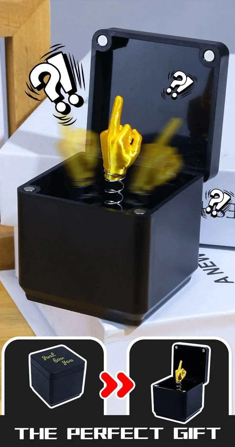 A black pop-up gift box is shown with a golden middle finger hand emerging from the top.