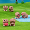 A group of cute mini hippo resin figurines in various poses sitting on a bright green grassy surface.