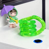 A small figure wearing a green hood and holding a purple umbrella stands next to a bright green, flexible fidget rope toy.