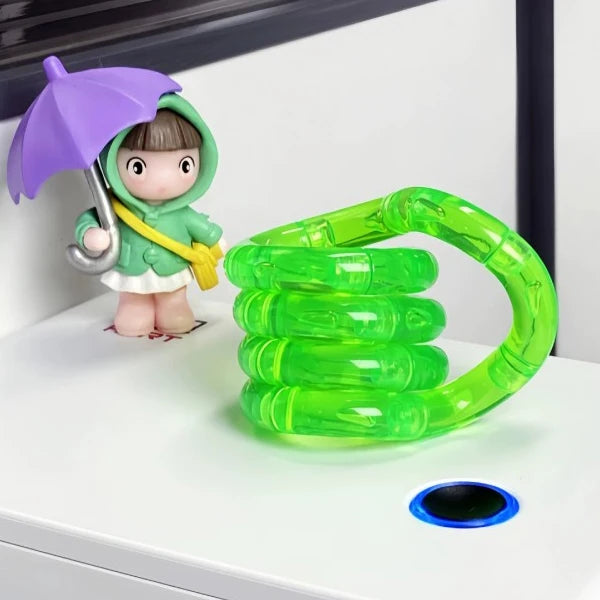 A small figure wearing a green hood and holding a purple umbrella stands next to a bright green, flexible fidget rope toy.
