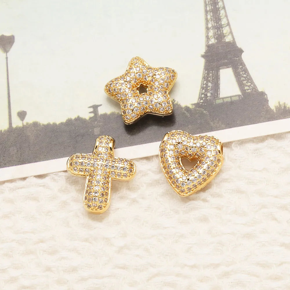 Gold tone crystal heart cross pendant jewelry displayed on a light background with the Eiffel Tower in the background